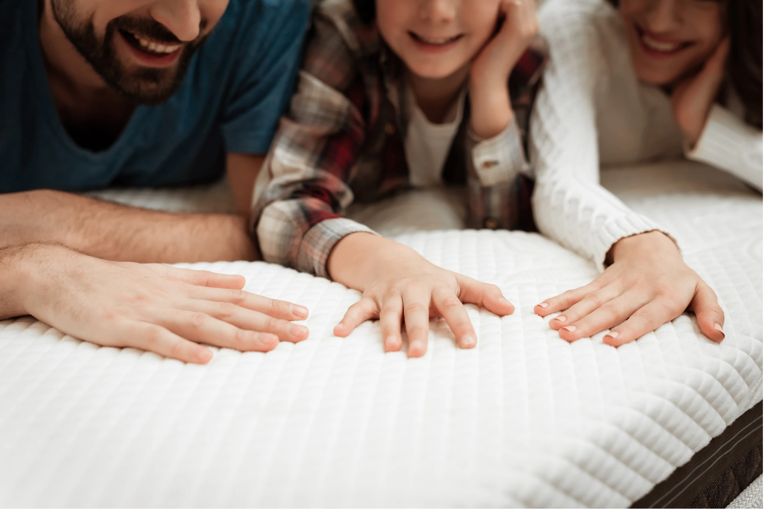 Une famille allongée sur le matelas teste sa douceur en touchant la surface avec la main