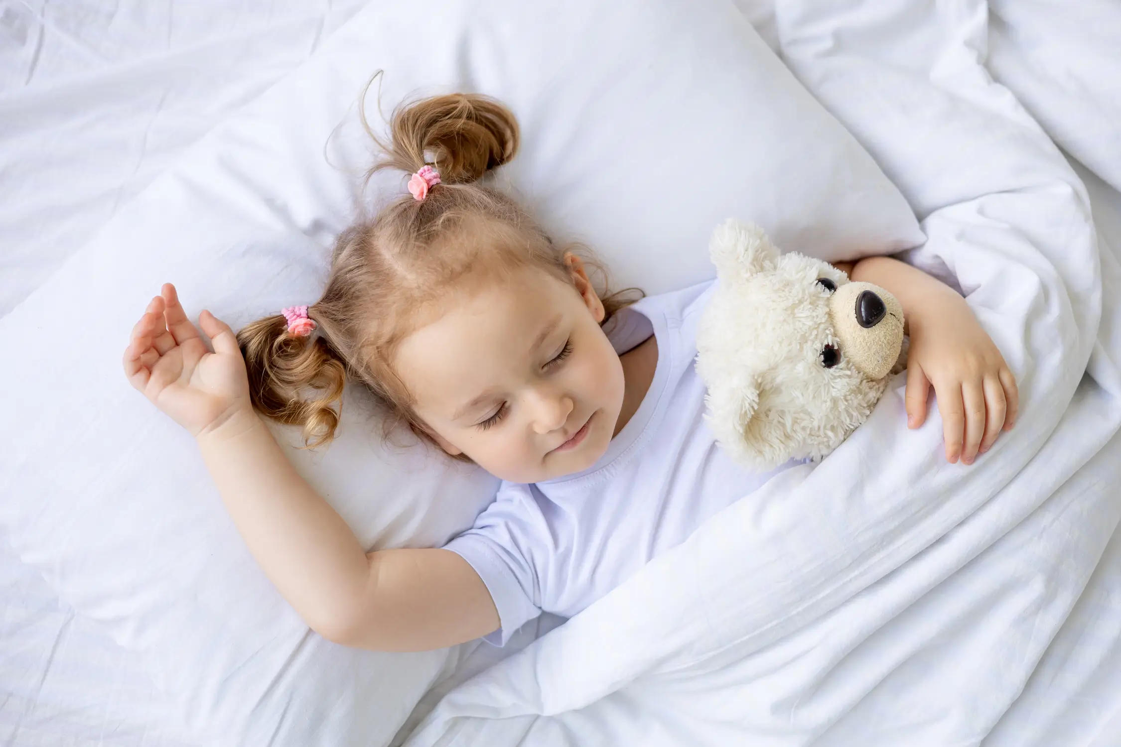 Enfant dormant paisiblement dans un lit, avec un doudou