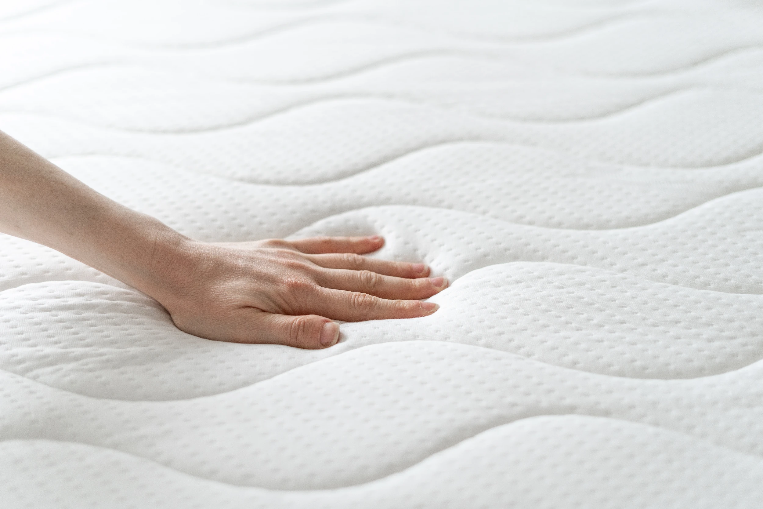 Main pressant la surface d’un matelas pour tester le moelleux