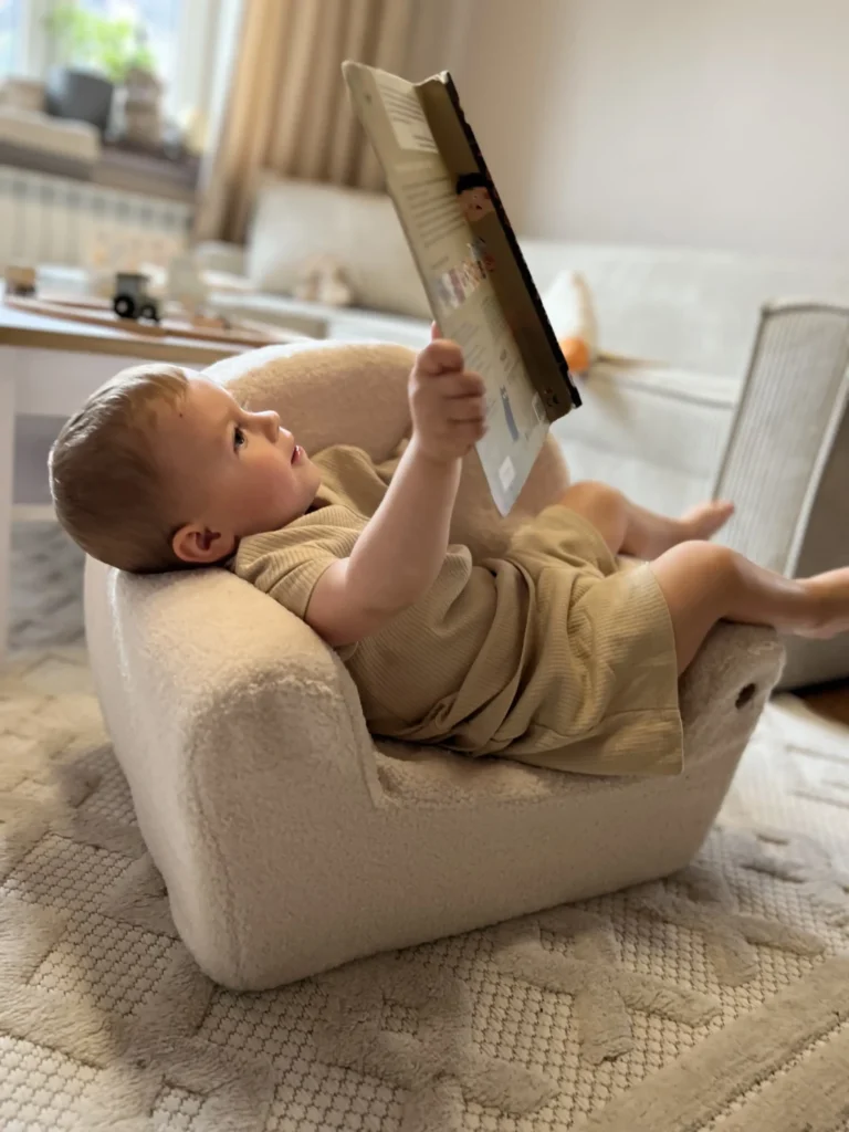 Enfant lisant un livre et assis sur un siège BUBU dans une chambre