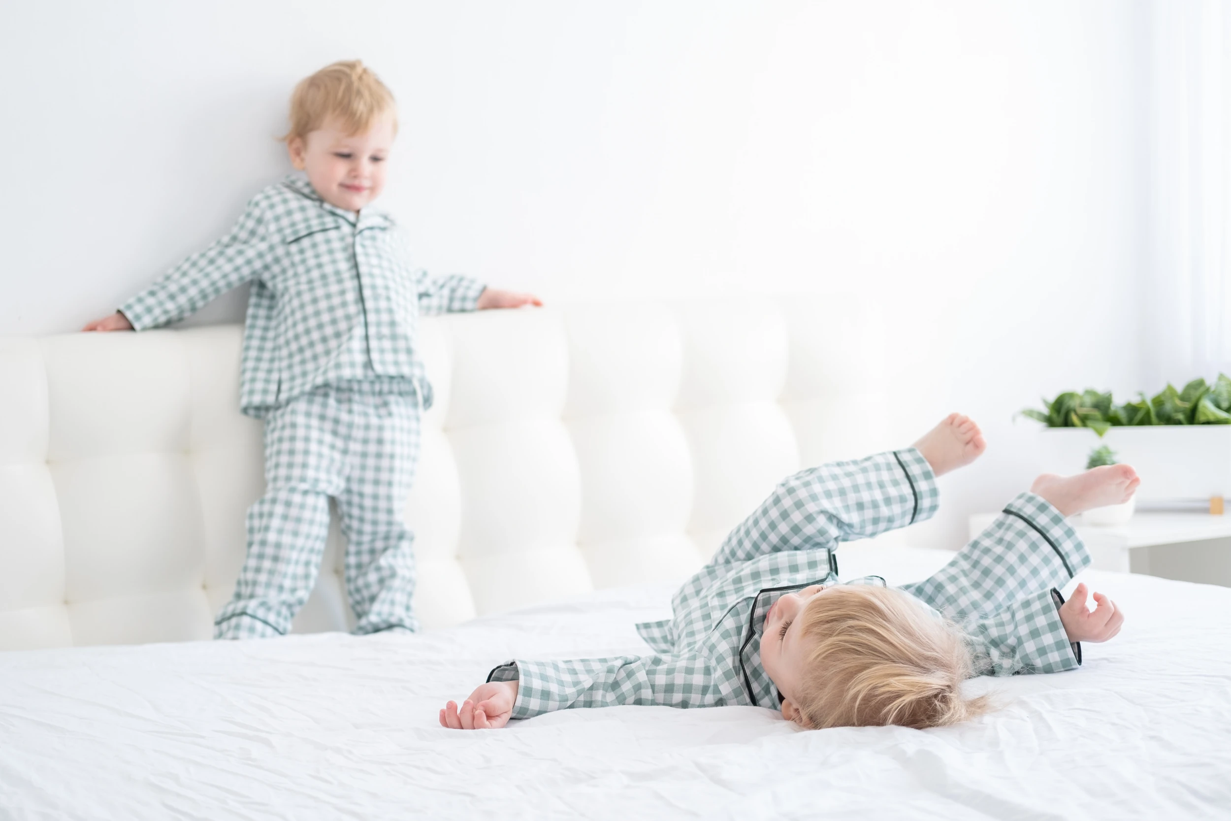 Deux jeunes enfants en pyjama jouent sur un grand lit