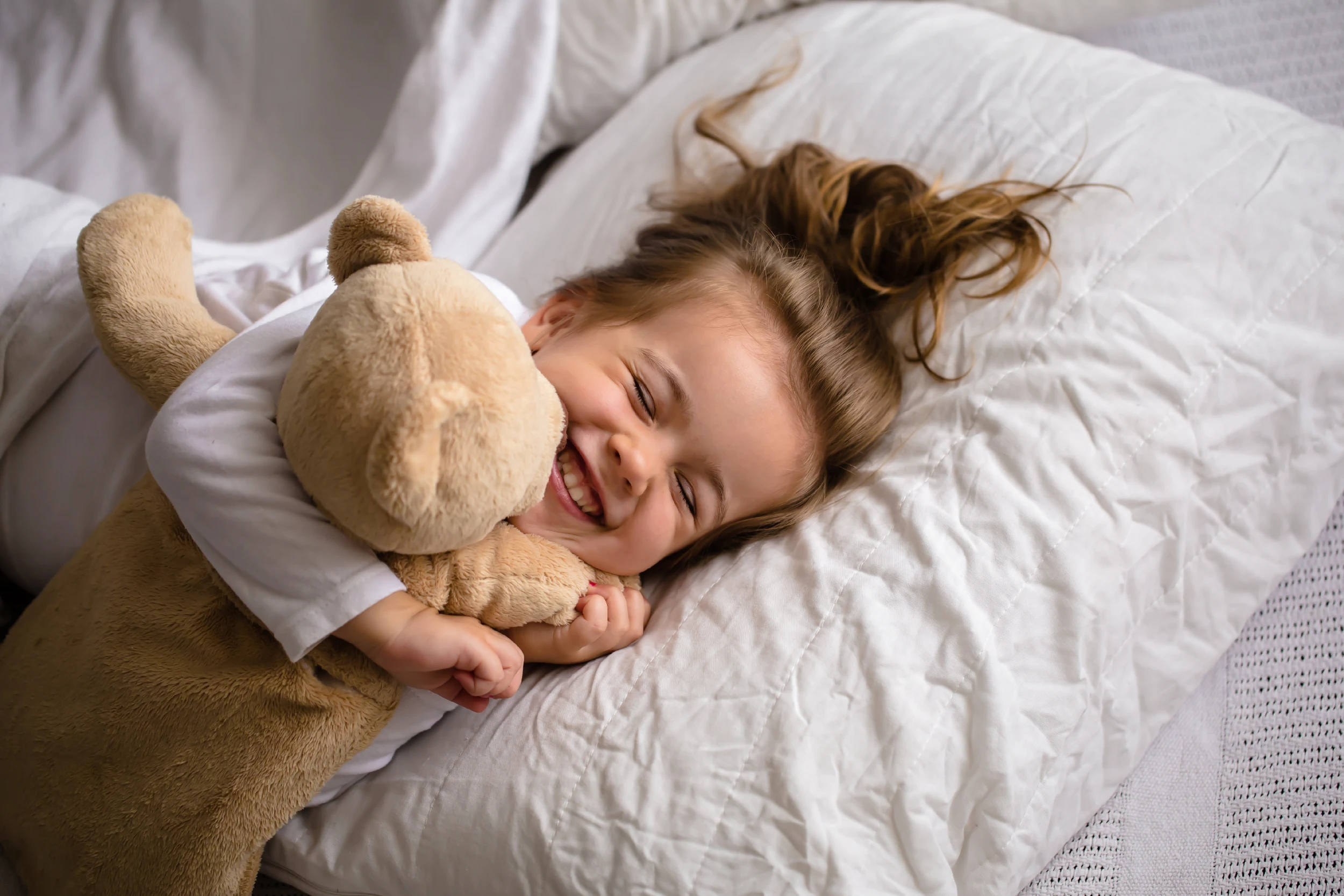 Enfant au lit avec un ours en peluche