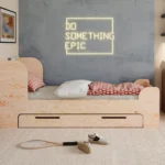 Letto per bambini in legno, realizzato in compensato di pino color legno naturale, con testiera alta e cassetto.