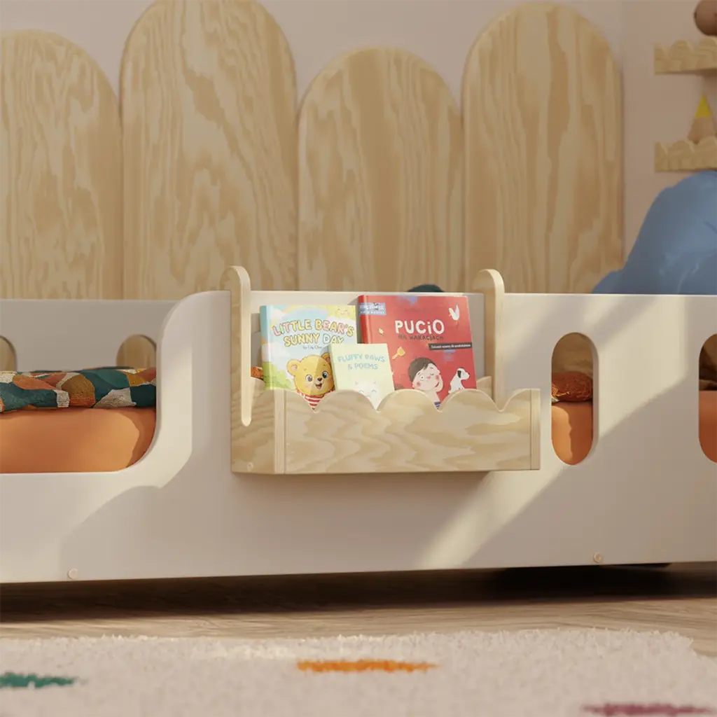 Mensola sospesa in legno naturale per libri per bambini LULI Montessori, fissata alla sponda del letto con libri esposti frontalmente.