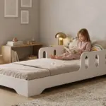 Bambina su letto bianco in cameretta minimalista con pareti TILA 6 bianca e giocattoli in legno.