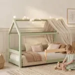 Letto a casetta MILO color verde salvia con baldacchino e luci, una bambina gioca con i cubi di legno sul tappeto.