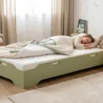 Letto per bambini TILA 8 color verde salvia, bassa struttura a terra, una bambina dorme con un coniglietto di peluche.