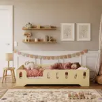 Letto per bambini TILA 2 giallo burro con barriere, bambina che dorme accanto a un dinosauro di peluche in una cameretta luminosa.