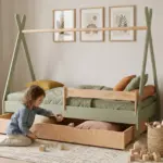 Letto tipi TIPI D verde in legno con cassetto estraibile, bambina che prende dei cubi dal cassetto in una cameretta luminosa.