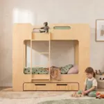 Letto a castello MIMI D in legno naturale con scala e cassetto, bambina che gioca con cubi di legno sul tappeto.