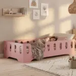 Letto per bambini Montessori TILA 2 color rosa con sponde ad asole, una bambina dorme con una coperta a cuori.