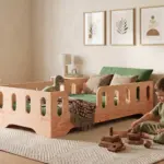Lettino TILA 2 in legno naturale con sponde, bambino che gioca con impilabili di legno sul tappeto accanto al letto.